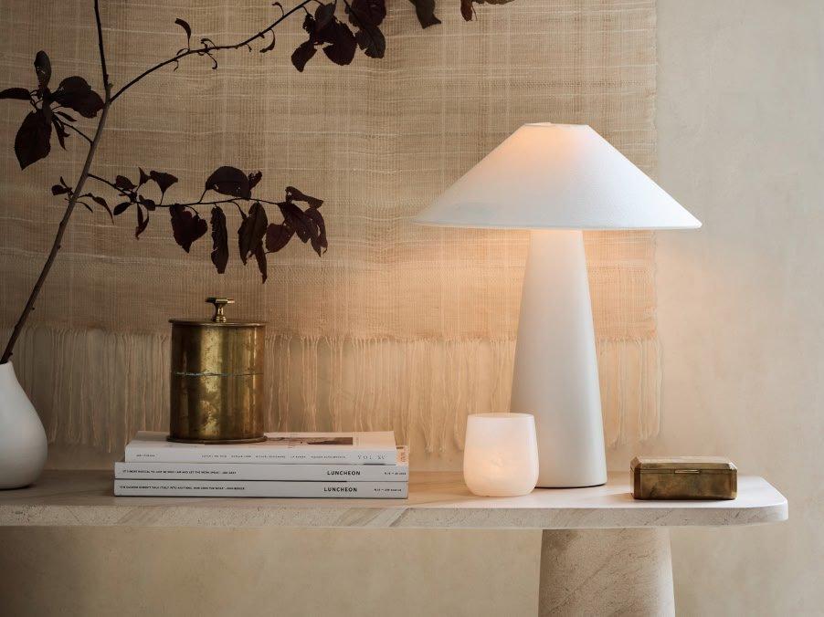 a table with a lamp, books, and a vase on it