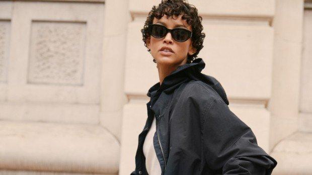 a woman in sunglasses and a jacket on a skateboard