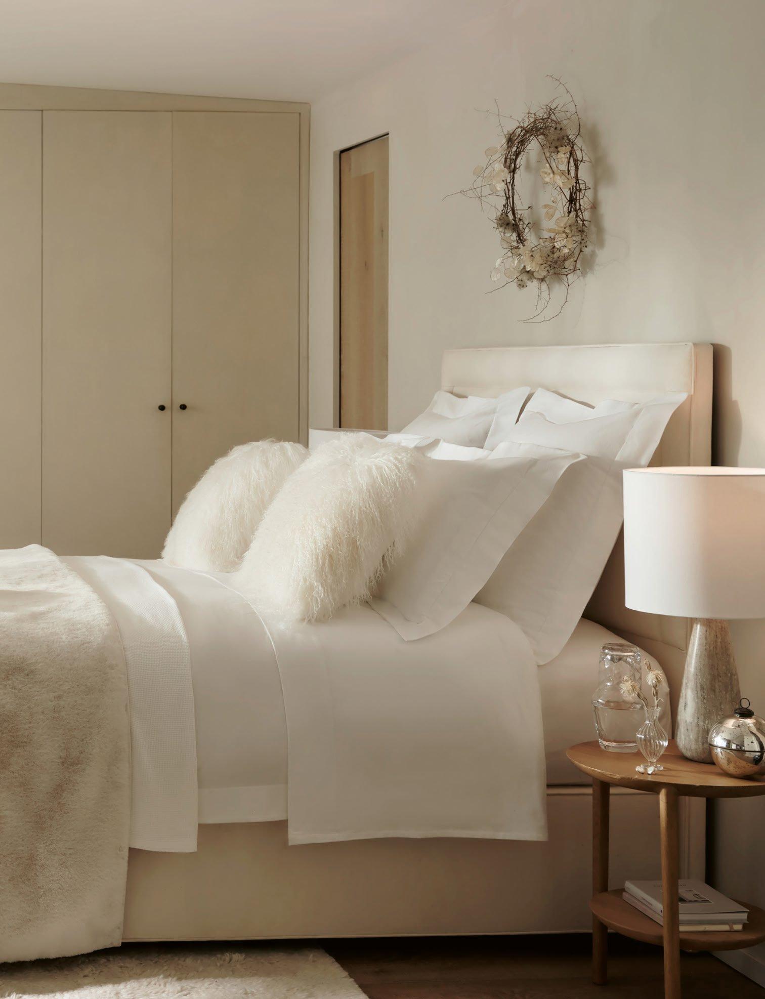 a bedroom with a white bed and a white nightstand