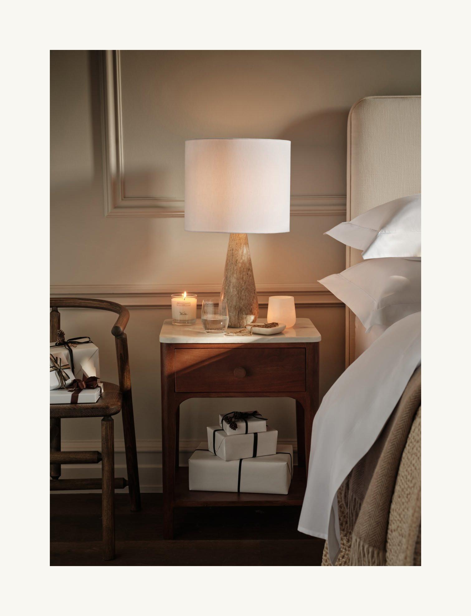 a bed with a white comforter and a white nightstan