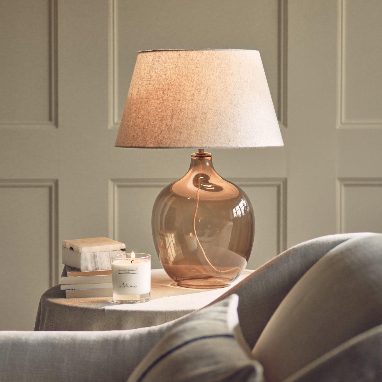 glass lamp on a table next to a candle