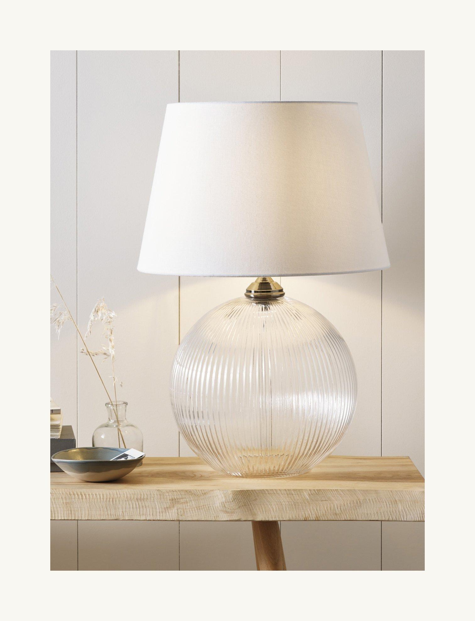 glass lamp on a table next to a bowl and vase