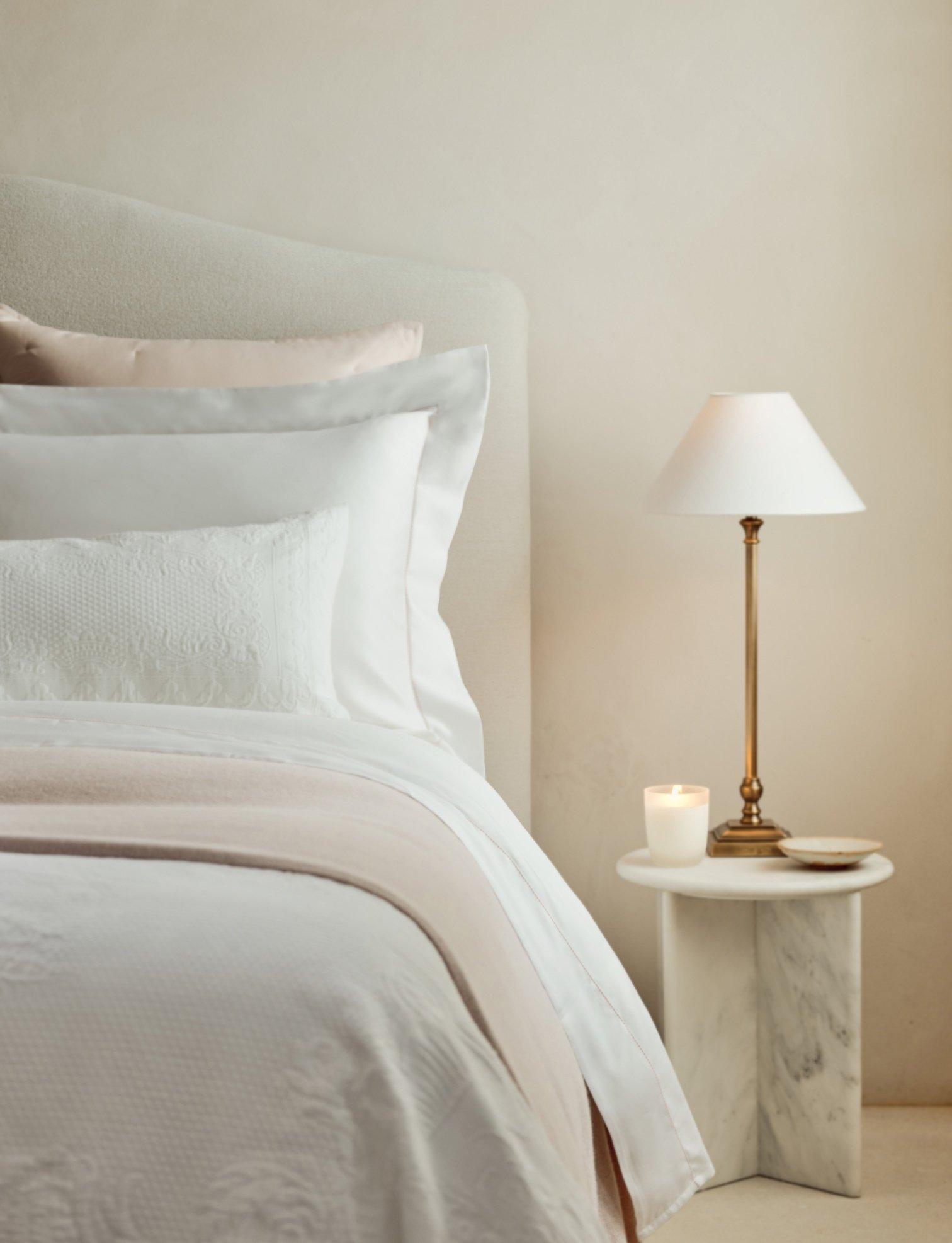 bedside lamp on a table next to a bed