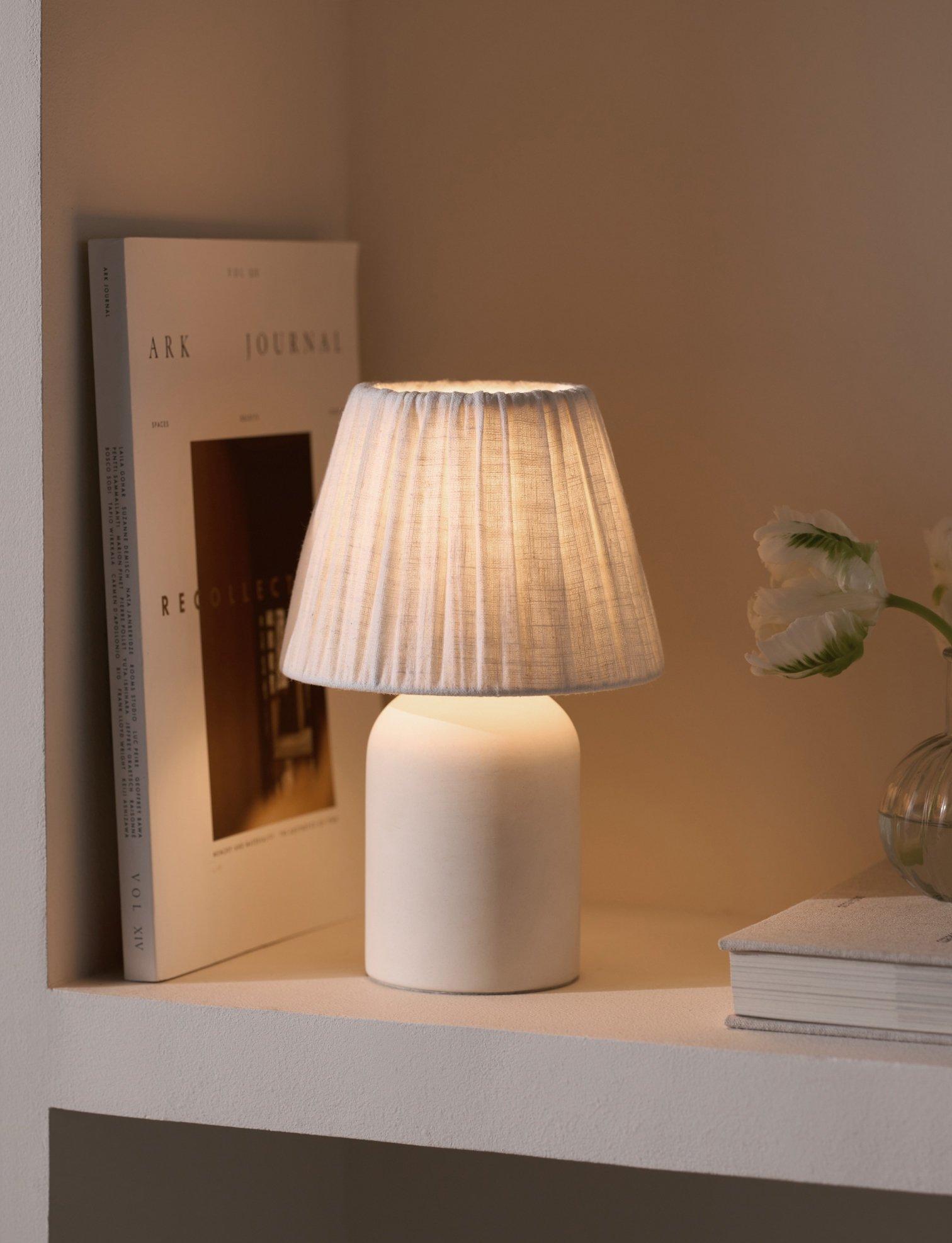 small white lamp on a shelf next to books