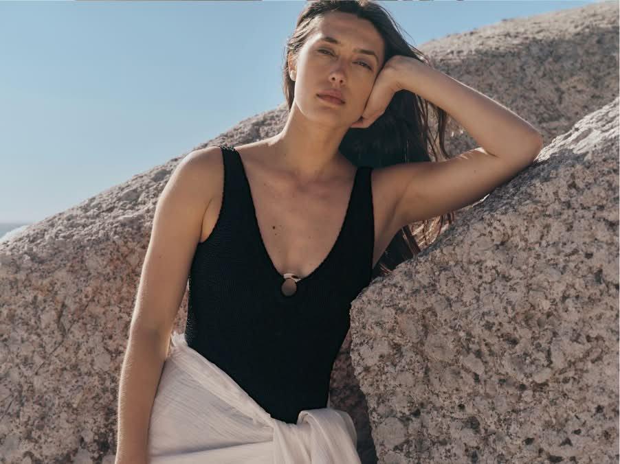 a woman standing on the beach with her arms crossed