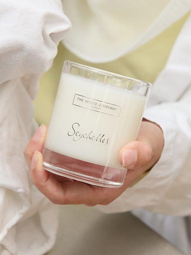 a person holding a candle in their hand while wearing a white shirt