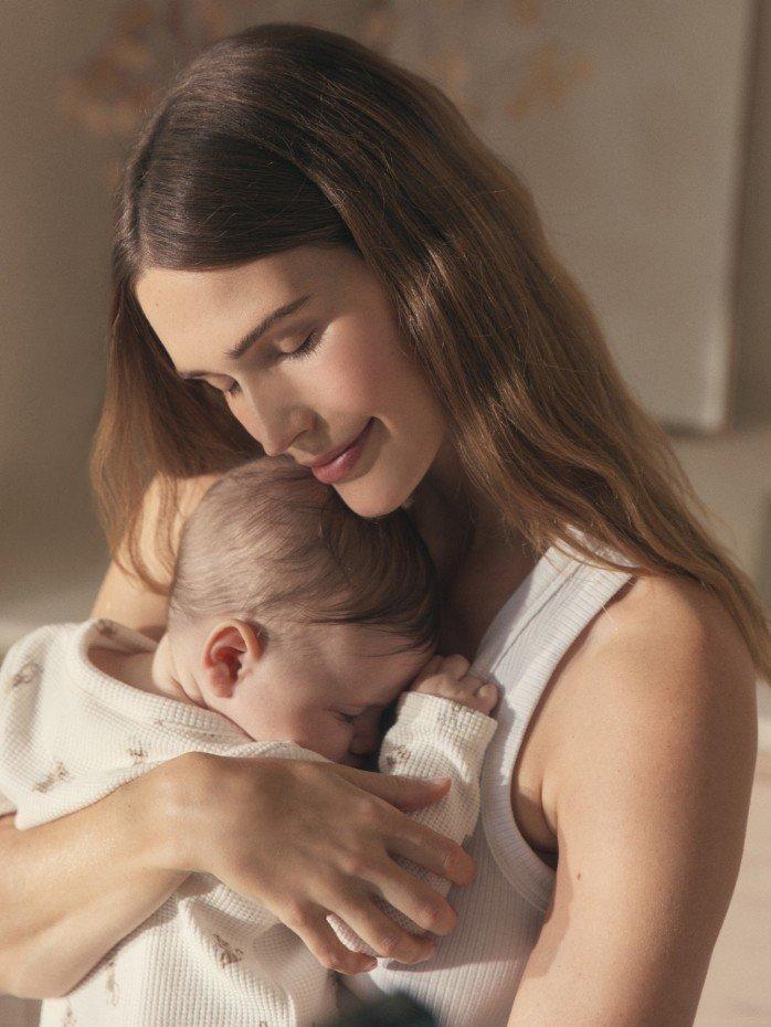 a woman holding a baby in a white shirt