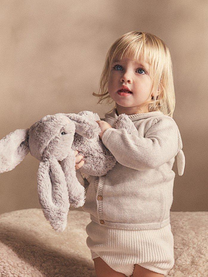 a young girl holding a stuffed rabbit on a couch