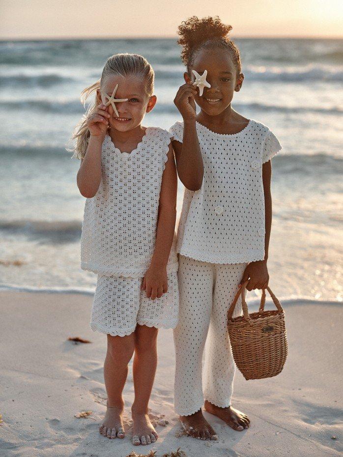 a little girl in white dress on beach with waves in background