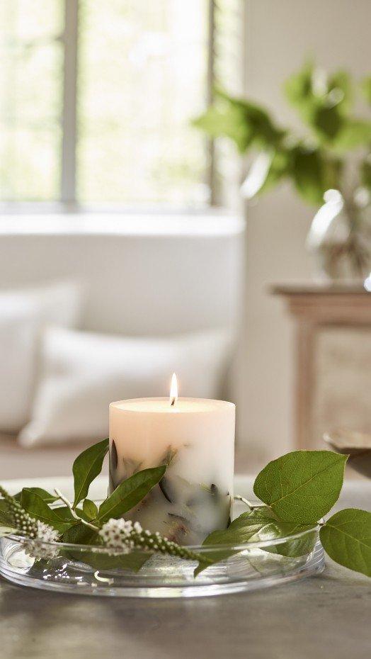 a candle on a table with a leaf and a flower