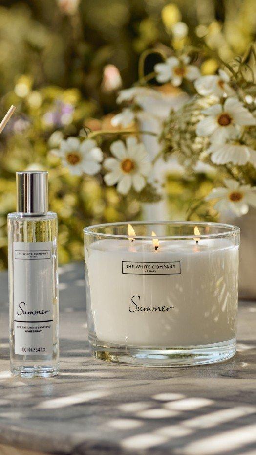 a candle and a bottle of perfume sit on a table