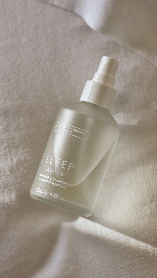a bottle of sleep spray on a white cloth on a bed