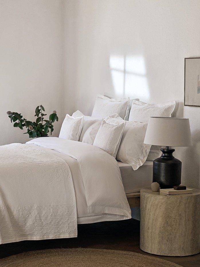 a bed with white sheets and pillows in a room with a skylight