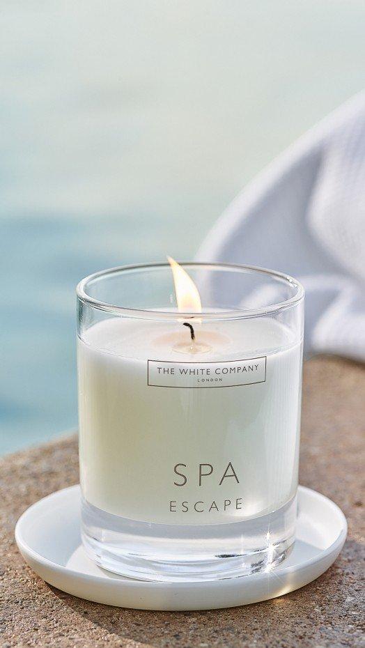 a candle sitting on a white plate next to a rock