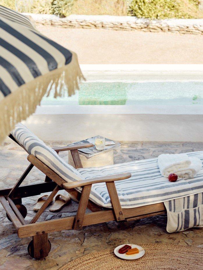 a chaise lounge with towels and a blanket on the ground