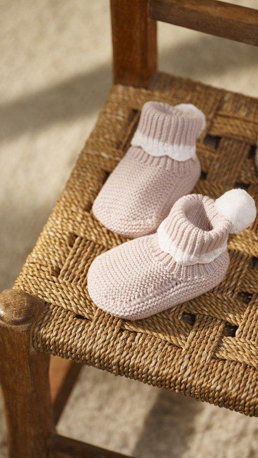 a pair of baby booties sit on a wooden chair