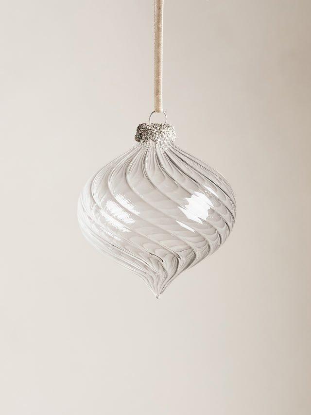 a glass ornament hanging from a string on a white wall