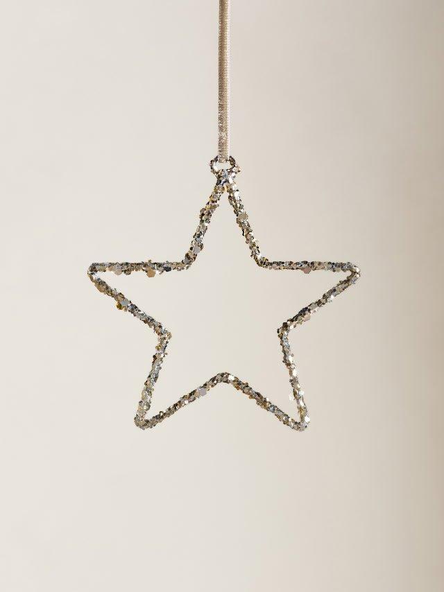 a silver star ornament hanging from a string