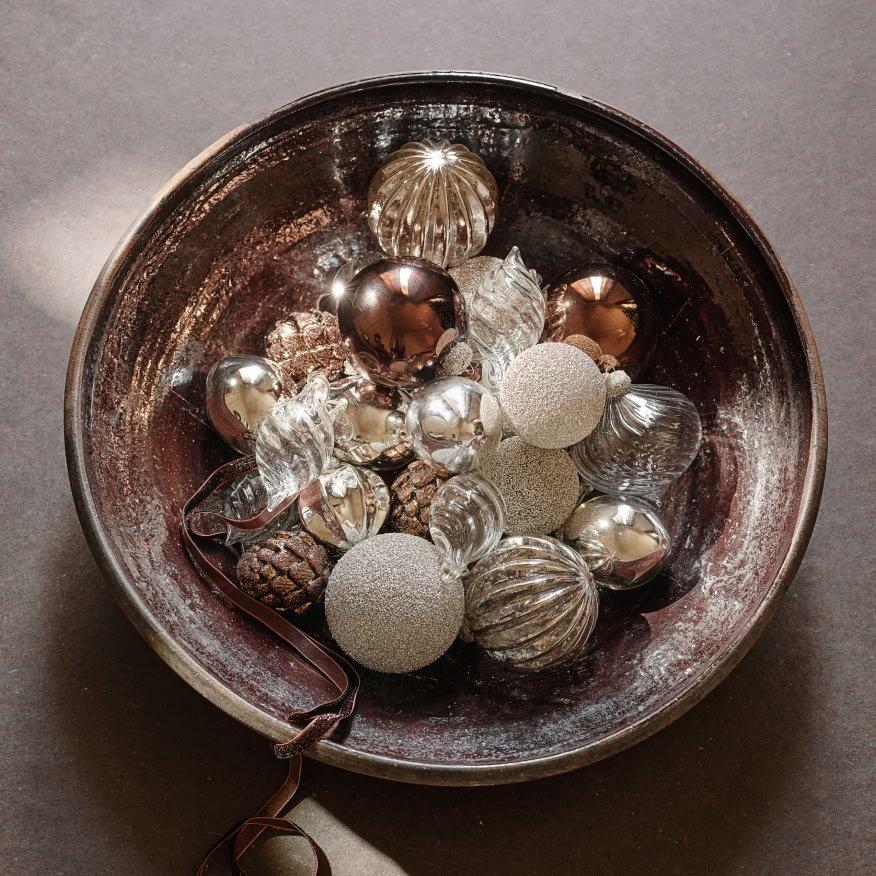 a bowl filled with silver and gold ornaments on a table