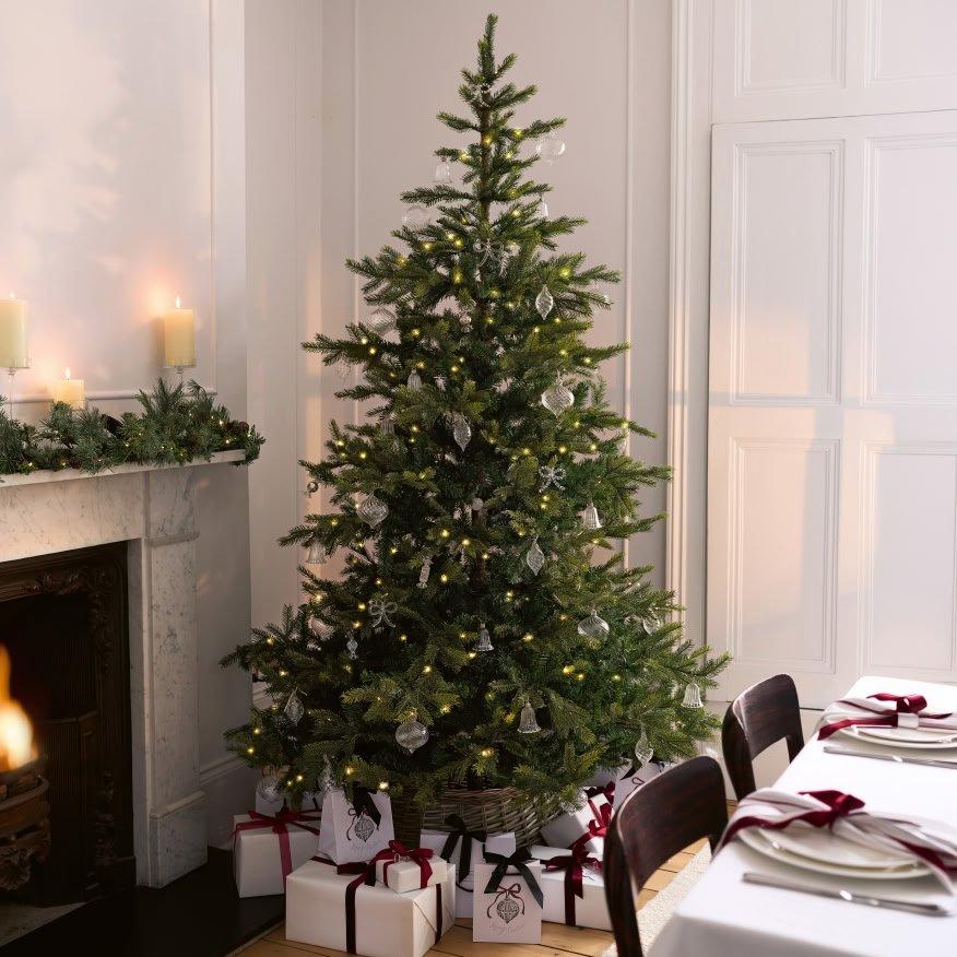 a christmas tree is lit in a room with a fireplace