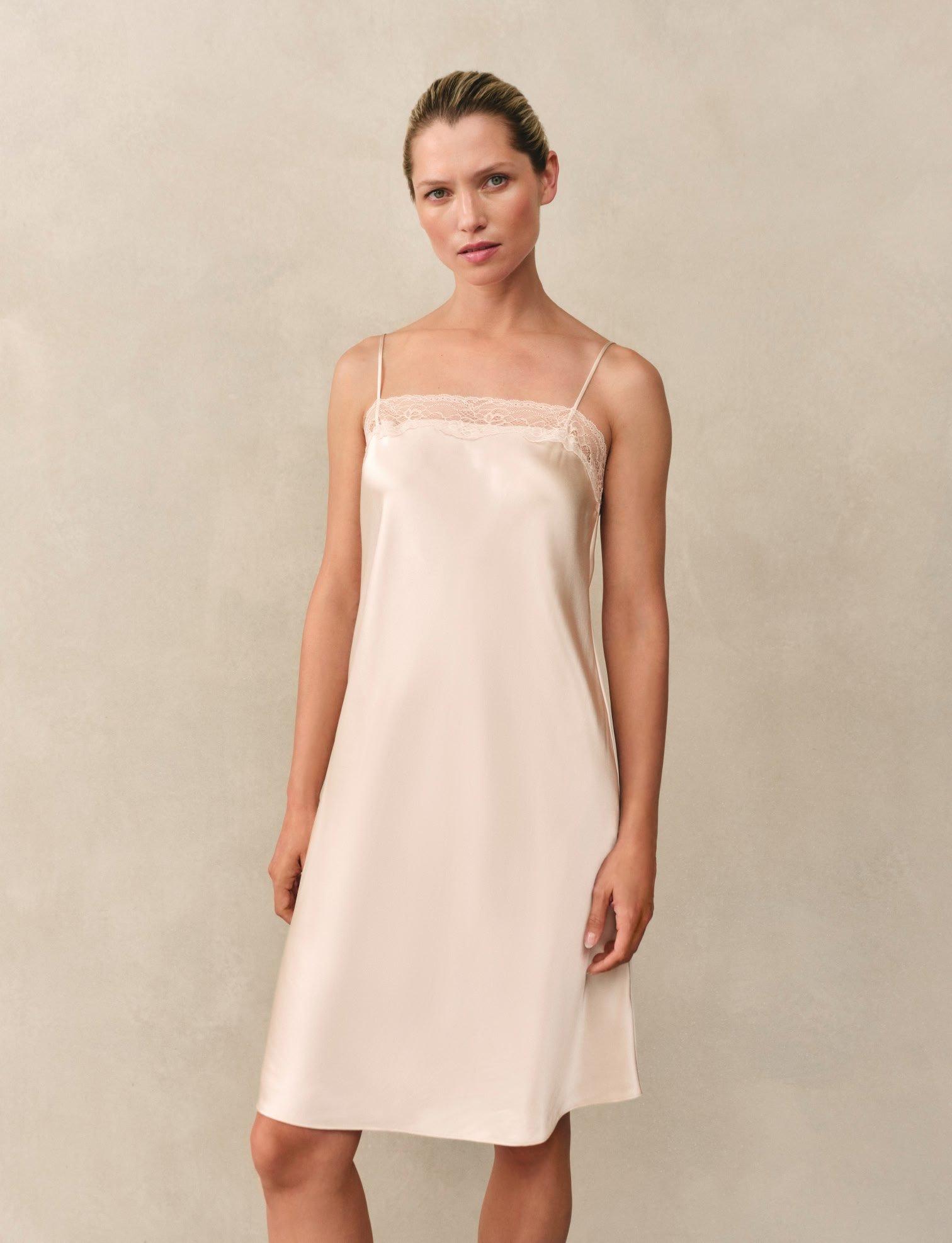 a woman in white pajamas sitting on a table with a tray of food