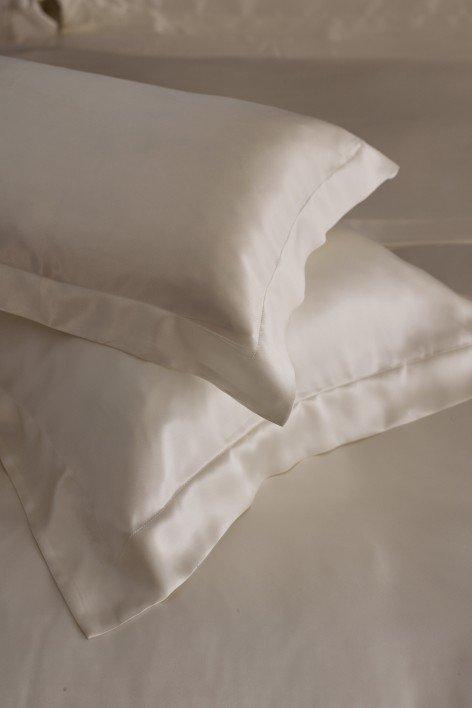 two white pillows on a bed with a white sheet