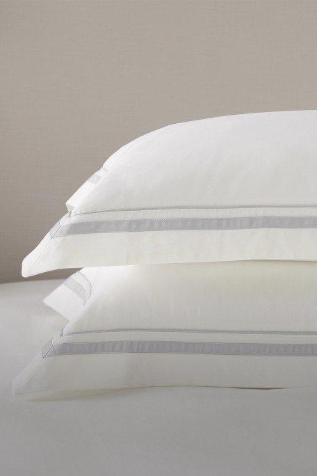 two pillows on a bed with a white sheet and a white pillow