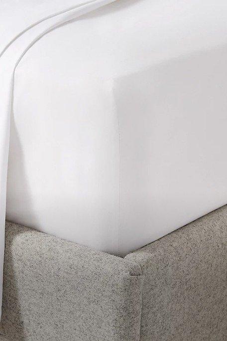 a bed with a white sheet and a white pillow on top