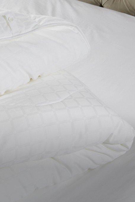 a bed with white sheets and pillows on a white bed