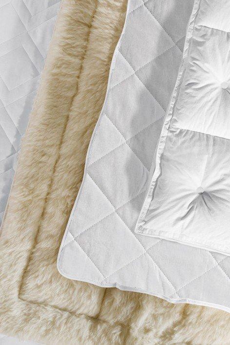 a close up of a white quilt on a bed with a white blanket