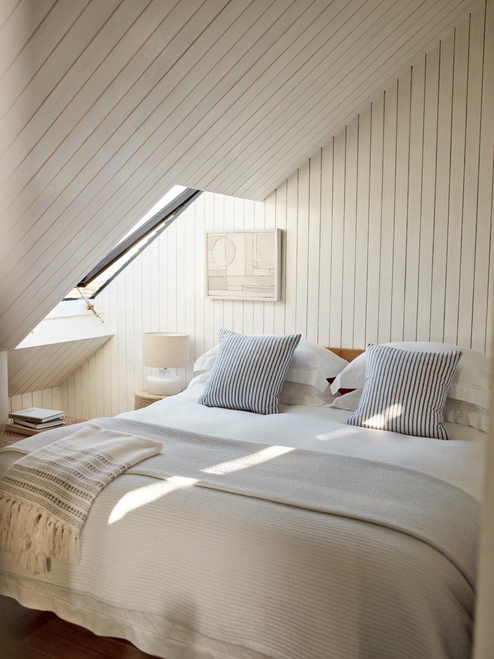 a bed in a bedroom with a white bedspread and pillows