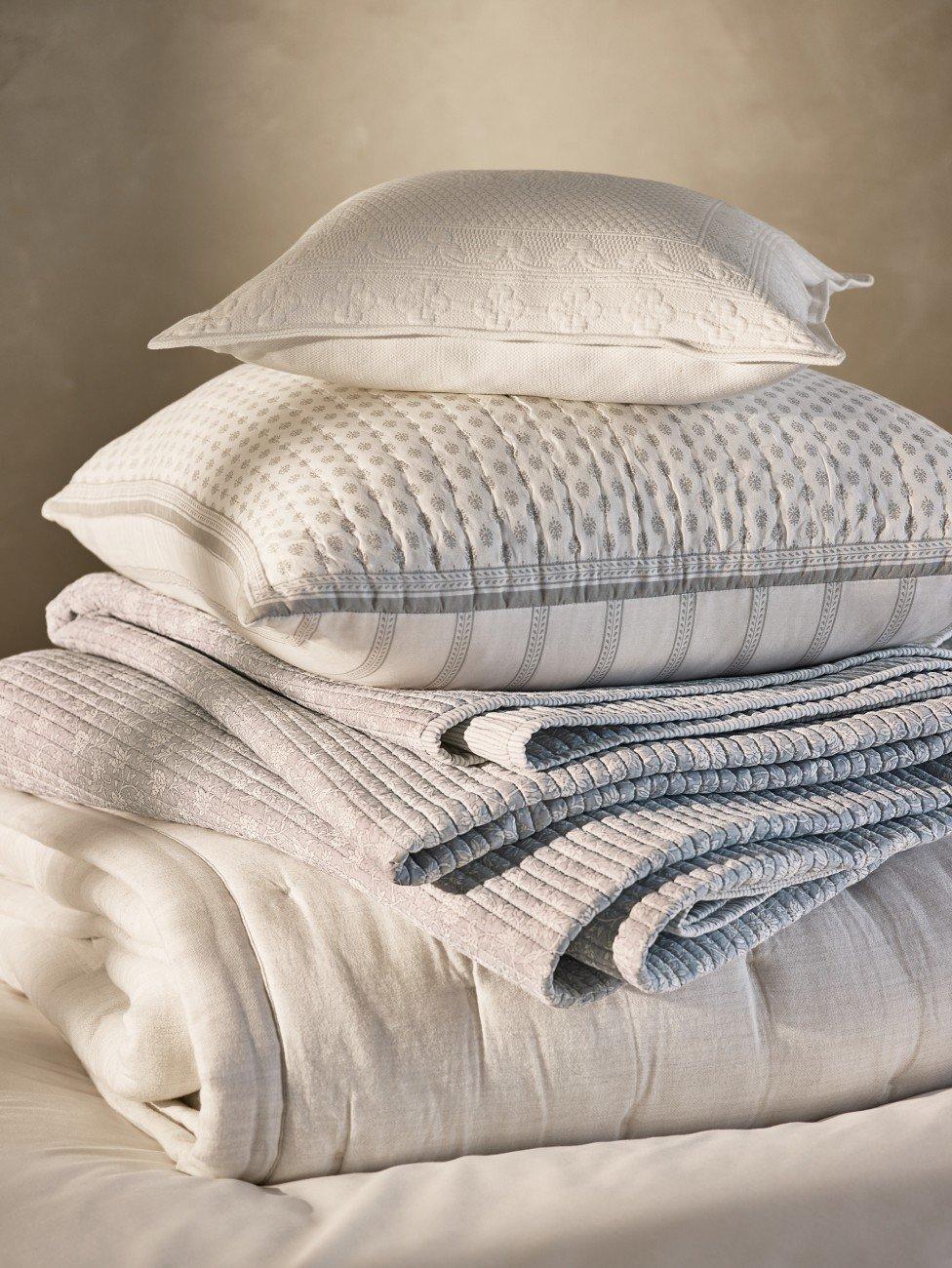 a stack of pillows on a bed with a white sheet