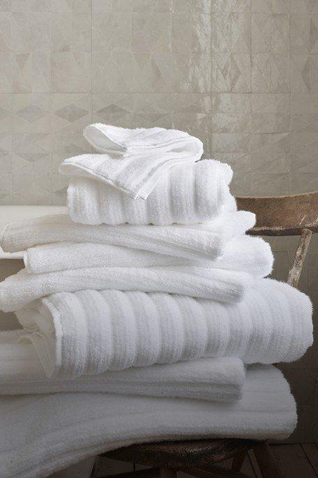 a stack of white towels sitting on a chair in a bathroom