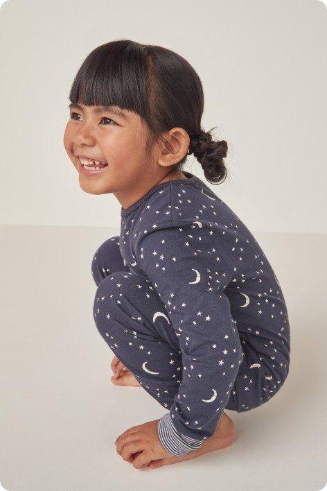 a little girl in a blue pajama with stars and moon on it