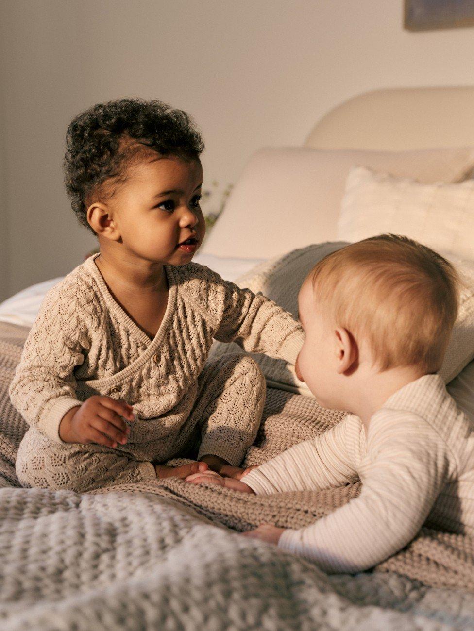 a woman holding a baby in a blanket in a bedroom