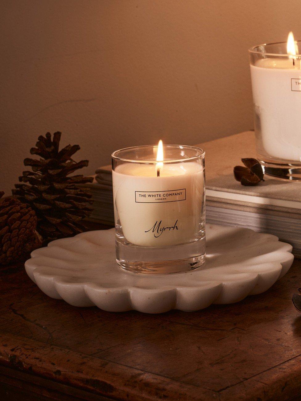 a candle on a plate with a candle on it next to a pine cone