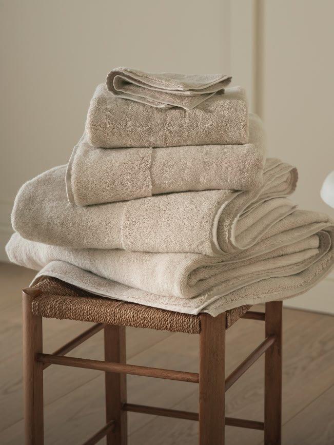 a stack of towels on a wooden stool in a bathroom