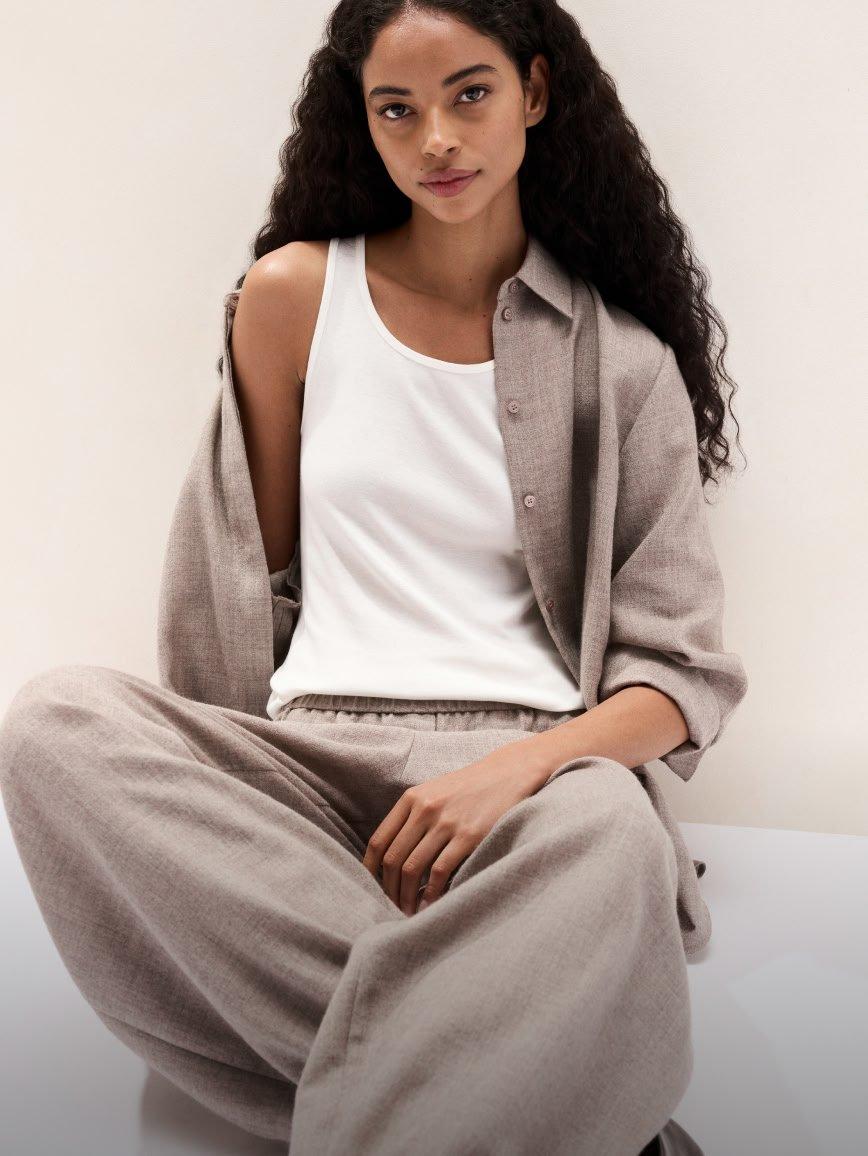 a woman in a white shirt and grey pants sitting on the floor