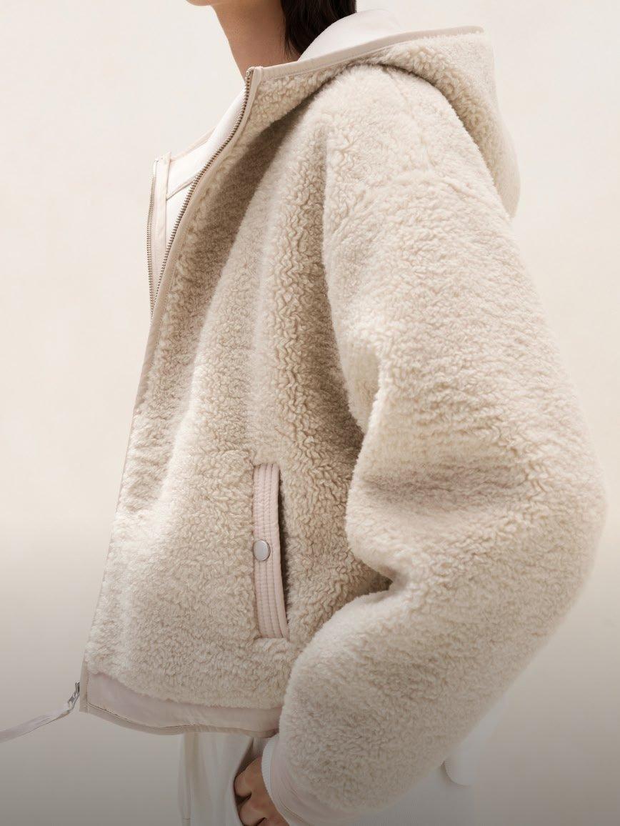 a woman in a beige jacket and white pants
