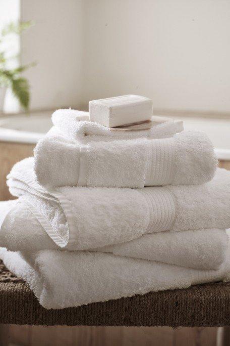 a stack of white towels sitting on top of a wooden chair