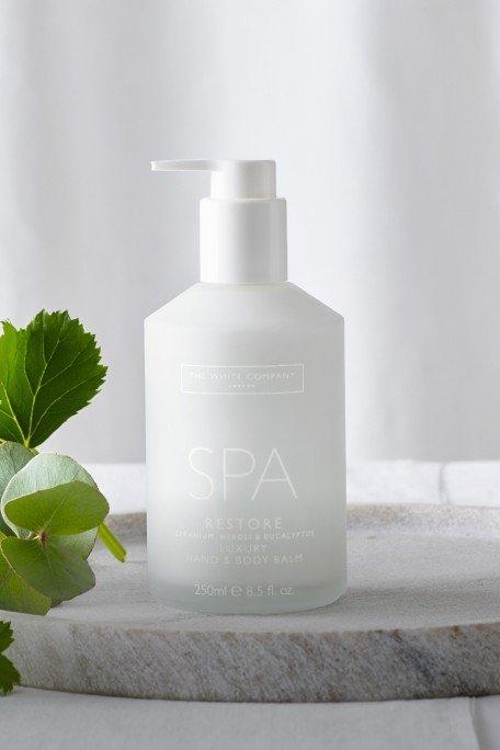 a bottle of spa lotion sitting on a plate next to a plant