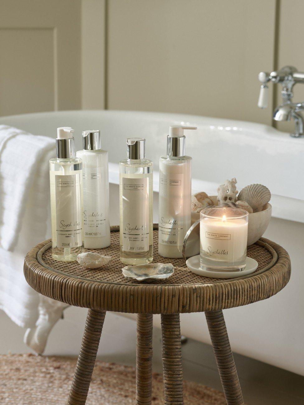 a bath salts and lotions are on a small table near a bathtub