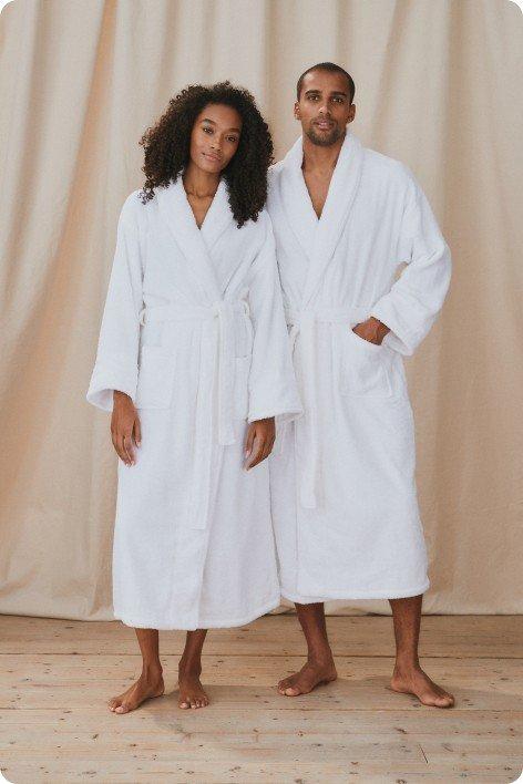 a man and woman in white bathrobes standing next to each other