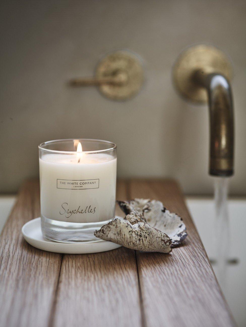 a candle sitting on a wooden table next to a faucet