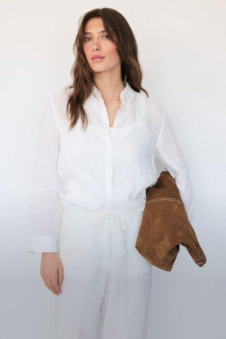 a woman in white is holding a brown leather bag