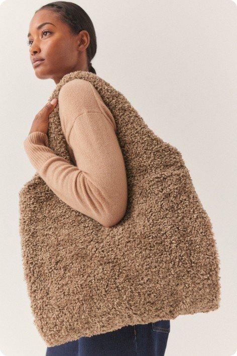 a woman is carrying a large fluffy tote bag