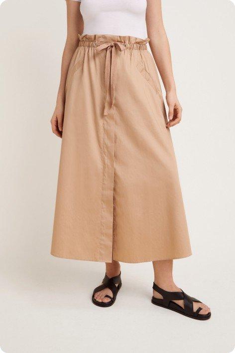 a woman is wearing a tan skirt and sandals