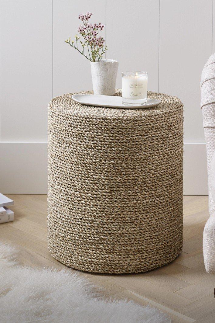 a round wicker stool with a candle on it in a room