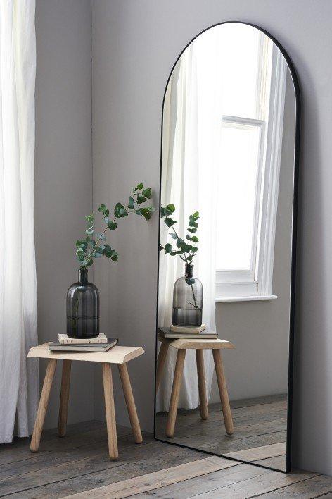 a mirror with a plant on a table next to a stool