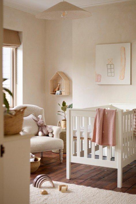 a bed with a white blanket and a small wicker basket